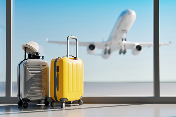 Luggage by a window at the airport with a plane taking off in the background