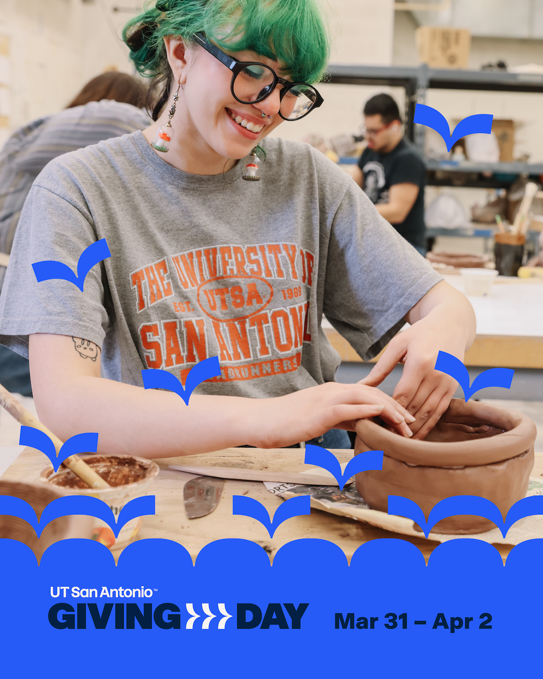Student smiling while throwing on a pottery wheel