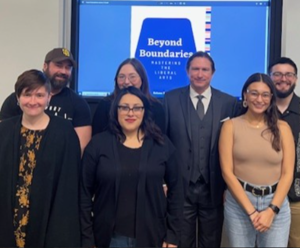 Graduate Students pose in front of Beyond Boundaries logo