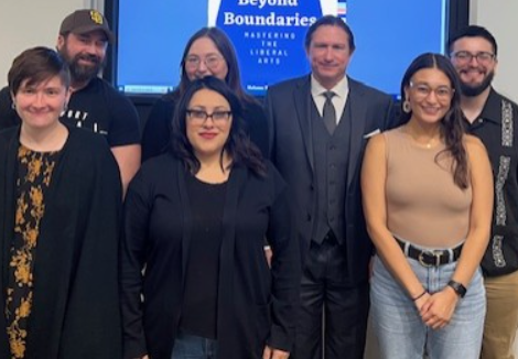 Graduate Students pose in front of Beyond Boundaries logo