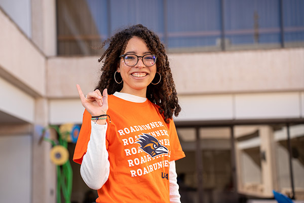 Philosophy student smiling and giving the UTSA roadrunner hand sign
