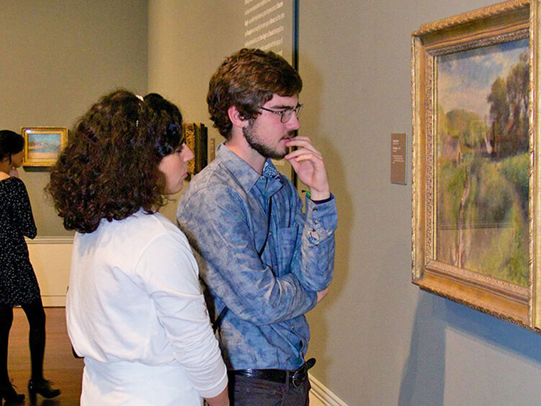 Two students looking at an art piece
