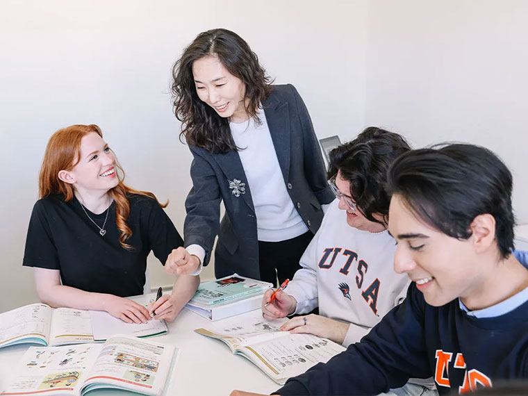 Professor standing over a table and talking to three students