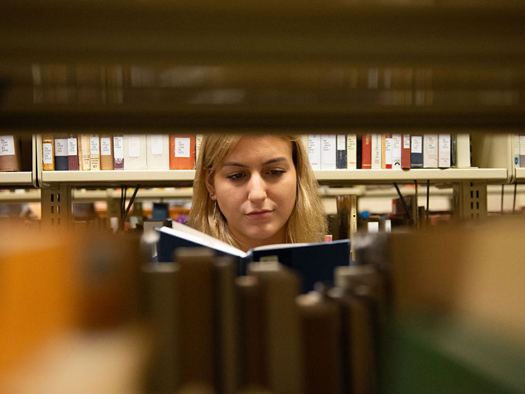 Student looking at a book in the library